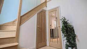 A wooden staircase with a glass railing leading to a second floor.