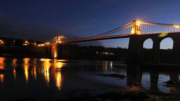 A bridge at night with lights reflecting on the water.