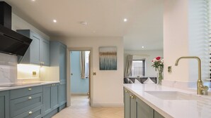 A modern kitchen with light blue cabinets, a white countertop, and a gold faucet.