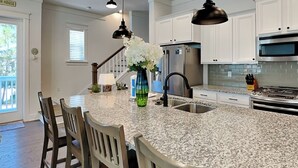 Een moderne keuken met granieten aanrechtbladen, roestvrijstalen apparatuur en witte keukenkastjes.