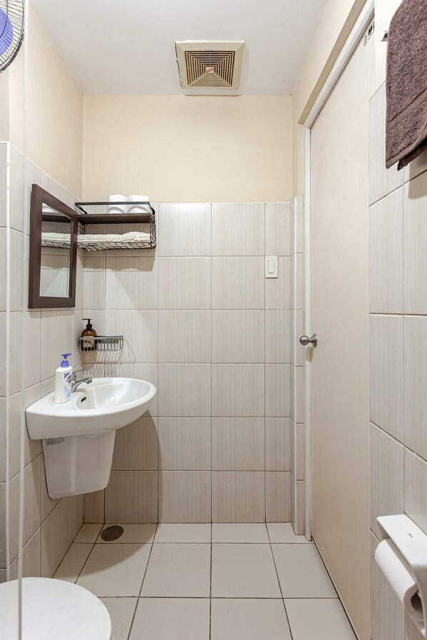 Un baño pequeño y limpio con un lavamanos, espejo y toallero blancos.