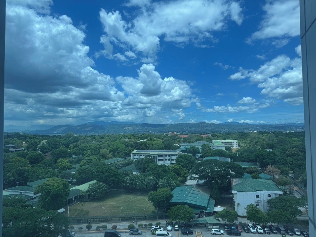 A view of a campus with multiple buildings, green spaces, and a parking area.