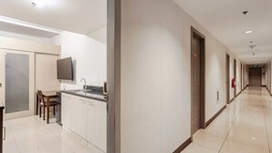 Ein Hotelkorridor mit Küchenzeile, einem Flachbildfernseher und einem Esstisch mit Stühlen.