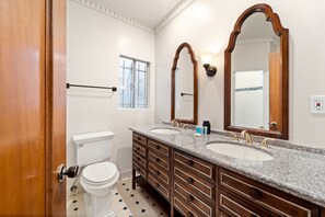 Een badkamer met twee wasbakken, een toilet en een raam.
