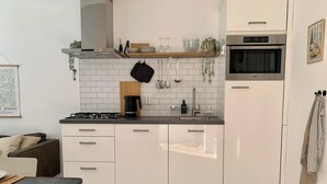 A modern kitchen with white cabinets, a black countertop, and a stainless steel oven.