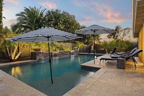 A pool area with two umbrellas, lounge chairs, and a waterfall feature. - Grand Camino Scottsdale Pool Retreat near Kierland (Scottsdale)