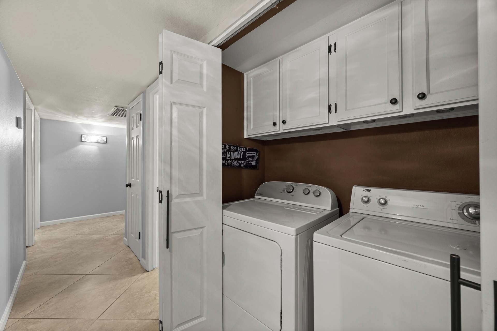 A laundry room with white cabinets, a washing machine, and a dryer.