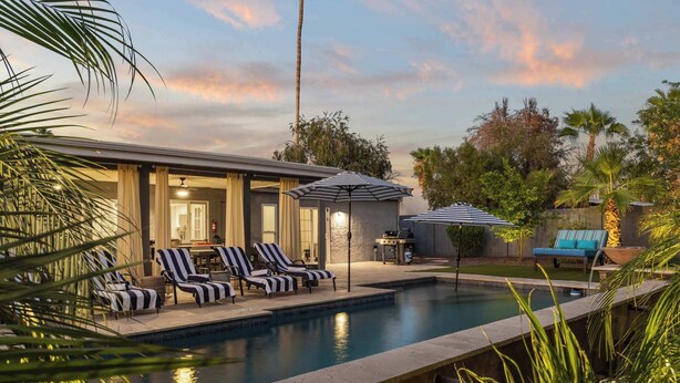 A pool area with lounge chairs and umbrellas, a barbecue grill, and a view of the surrounding greenery. - Grand Camino: Stylish Vibes, Pool, Grille, Firepit (Scottsdale)