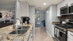 A modern kitchen with granite countertops, stainless steel appliances, and a view to the living area. - Grand Camino: Stylish Vibes, Pool, Grille, Firepit (Scottsdale)
