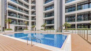 A modern building with a swimming pool, surrounded by palm trees and potted plants. - GLOBALSTAY Azizi Riviera 59 (Dubai)
