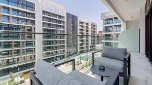 A modern apartment with a balcony, large windows, and a view of surrounding buildings. - GLOBALSTAY Azizi Riviera 59 (Dubai)
