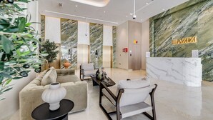 A modern lobby with a marble reception desk, plush seating, and a large potted plant. - GLOBALSTAY Azizi Riviera 59 (Dubai)