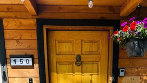 A wooden door with a number plate, a welcome mat, and a bear decoration. - Nvh0650 - Woodland Escape 2 Bedroom Home (Stateline)