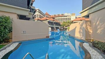 Una piscina al aire libre, sombrillas, sillones reclinables de piscina