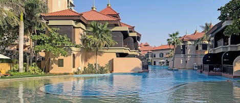 Een buitenzwembad, parasols bij het zwembad en ligstoelen