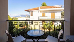 Varanda com mesa redonda e duas cadeiras, vista para área residencial com casas e céu claro.
