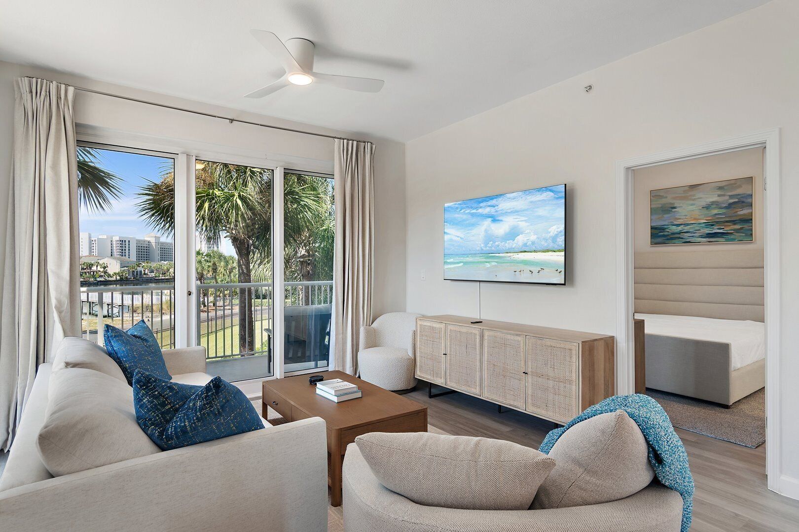 A modern living room with a balcony, a flat-screen TV, and a painting on the wall.