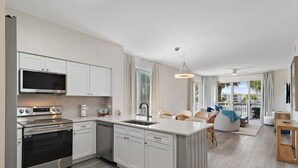 A modern kitchen with white cabinetry, stainless steel appliances, and a central island. - Terrace At Pelican Beach 0107 3 Bedroom Condo (Destin)