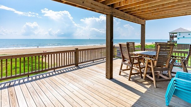 Een houten terras met uitzicht op het strand en de oceaan.