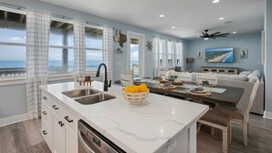 Een moderne keuken met een groot schiereiland, een eethoek en uitzicht op de oceaan.