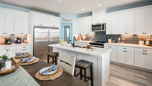 Een moderne keuken met witte kasten, een centraal eiland, roestvrijstalen apparatuur en een blauwe accentmuur.