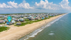 Luchtbeeld van een kustbewoonbaar gebied met huizen aan het strand, een heldere lucht en een kalme zee.