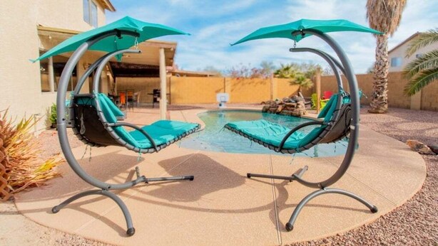 A poolside area with two swing chairs and a small pool. - Casa Aria 4br Home & Heated Pool 4 Bedroom Home (Casa Grande)
