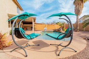 A poolside area with two swing chairs and a small pool. - Casa Aria 4br Home & Heated Pool 4 Bedroom Home (Casa Grande)