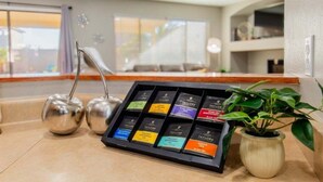 A tea station with multiple tea options, a plant, and a seating area in the background. - Casa Aria 4br Home & Heated Pool 4 Bedroom Home (Casa Grande)