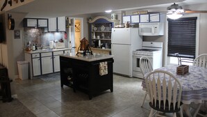 A kitchen with white cabinets, a central island, a microwave, and a dining table with chairs. - Step Back In Time to a charming 2-bedroom lower level house in adorable Eudora (Eudora)