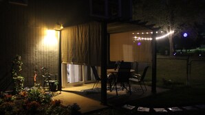 A covered patio area with a table and chairs, surrounded by a garden with various plants. - Step Back In Time to a charming 2-bedroom lower level house in adorable Eudora (Eudora)