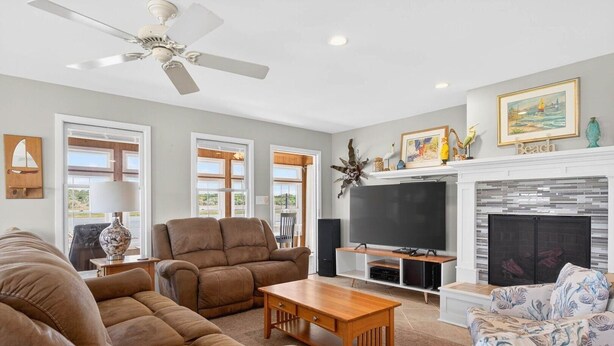 A spacious living room with a fireplace, comfortable seating, and a television. - Island Time 3 Bedroom Home (Supply)