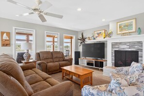 A spacious living room with a fireplace, comfortable seating, and a television. - Island Time 3 Bedroom Home (Supply)