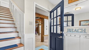 A staircase with wooden steps and blue mats, leading to a dark blue door with a glass panel. - Island Time 3 Bedroom Home (Supply)