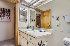 Ein Badezimmer mit Waschbecken, Spiegel, Holztür und Toilette.