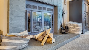 A fireplace with logs, a wicker chair, and a cabinet. - Village At Breck Antero 1504 1 Bedroom Condo (Breckenridge)