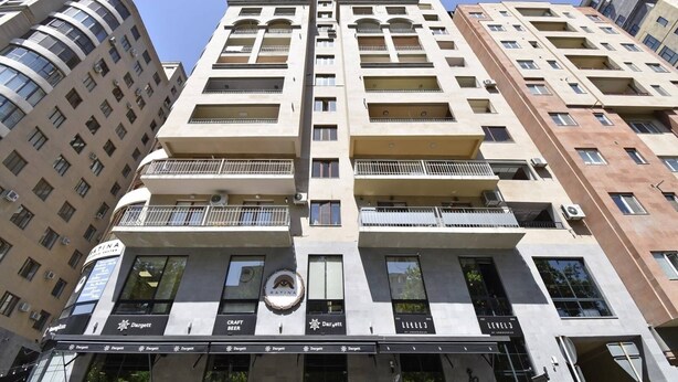 Un immeuble à plusieurs étages doté d’une entrée centrale, de nombreux balcons et d’une enseigne « Dargett Craft Beer » au niveau du rez-de-chaussée.