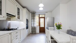 Une cuisine avec des meubles blancs, une cuisinière et un coin repas comprenant une table et des chaises.