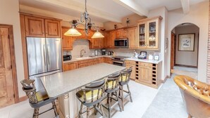 A spacious kitchen with wooden cabinets, a large island with bar stools, stainless steel appliances, and a skylight. - Aspen Downtown 2BR Ski Condo w/ Fireplace - CD 17 (Aspen)