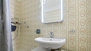 A bathroom with a white sink, a mirror, and patterned wallpaper. - Crans-Montana - Studio ski 2 pers - 3 min Cry d'Er (Crans-Montana)