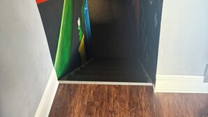 A narrow hallway with a wooden floor and a dark wall featuring a colorful mural. - Charming 4 Bedroom, Fire Pit, Outdoor Projector, Heated Pool, Close to Downtown (Washington)