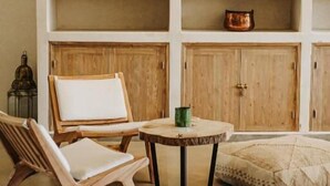 Una habitación con una silla de madera, una mesa redonda y un estante con objetos decorativos.