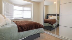 Un dormitorio con cama, un espejo grande y un armario.