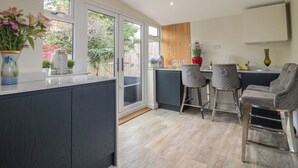 Cocina moderna con una isla grande, taburetes de bar y vistas al jardín a través de amplios ventanales.