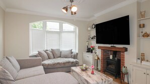 Una sala de estar con un sofá modular, una mesa de centro de mármol, una chimenea y un televisor de pantalla plana montado encima.