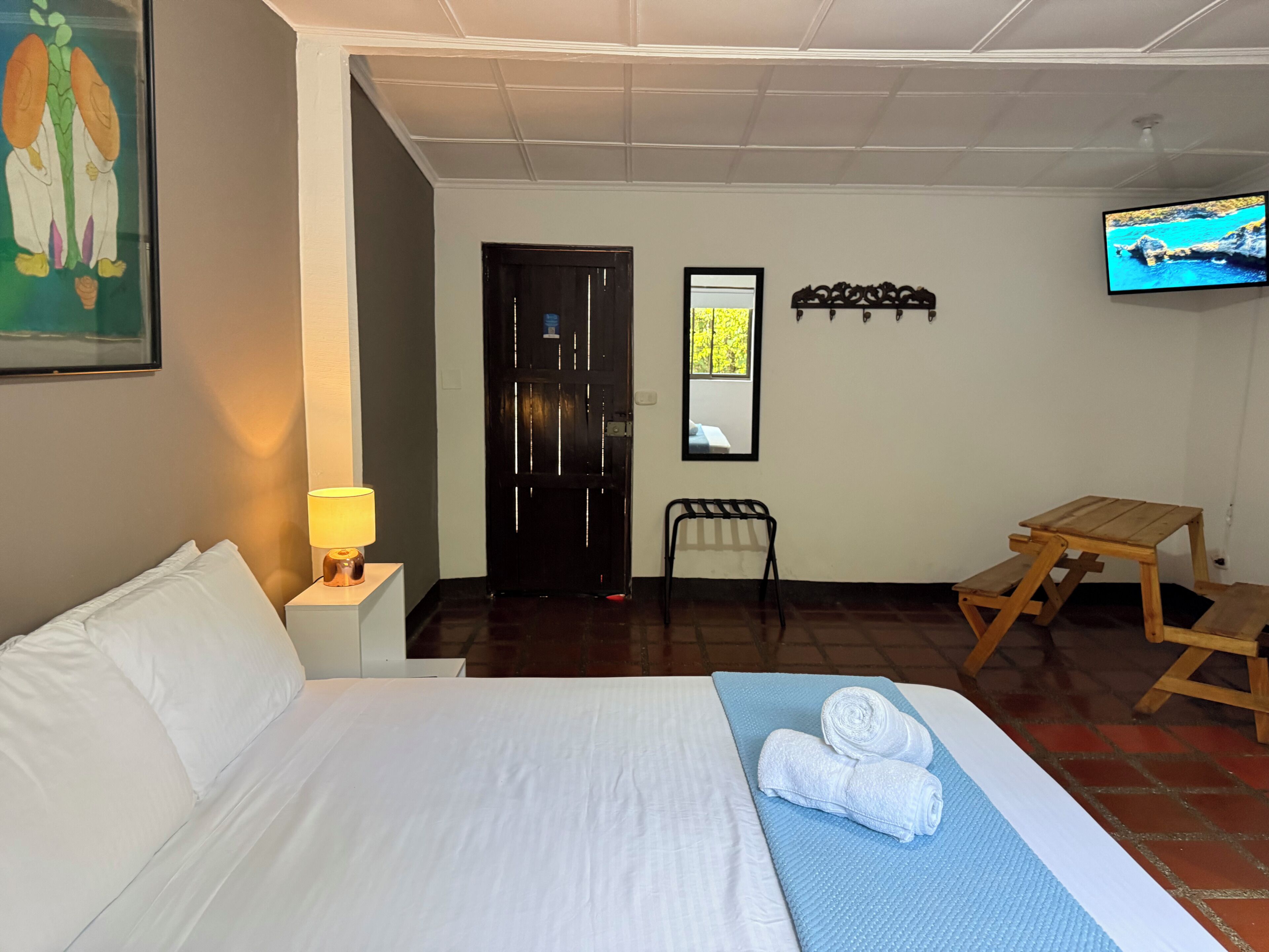 Una habitación de hotel con cama, televisor, escritorio y silla.