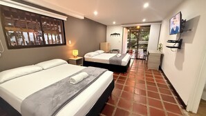 A hotel room with two beds, a desk, a chair, a TV, and a view of the outdoors. - Hotel CSI Llanogrande (Rionegro)