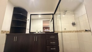 A bathroom with a dark wood vanity, a glass shower enclosure, and a tiled backsplash. - Hotel CSI Llanogrande (Rionegro)