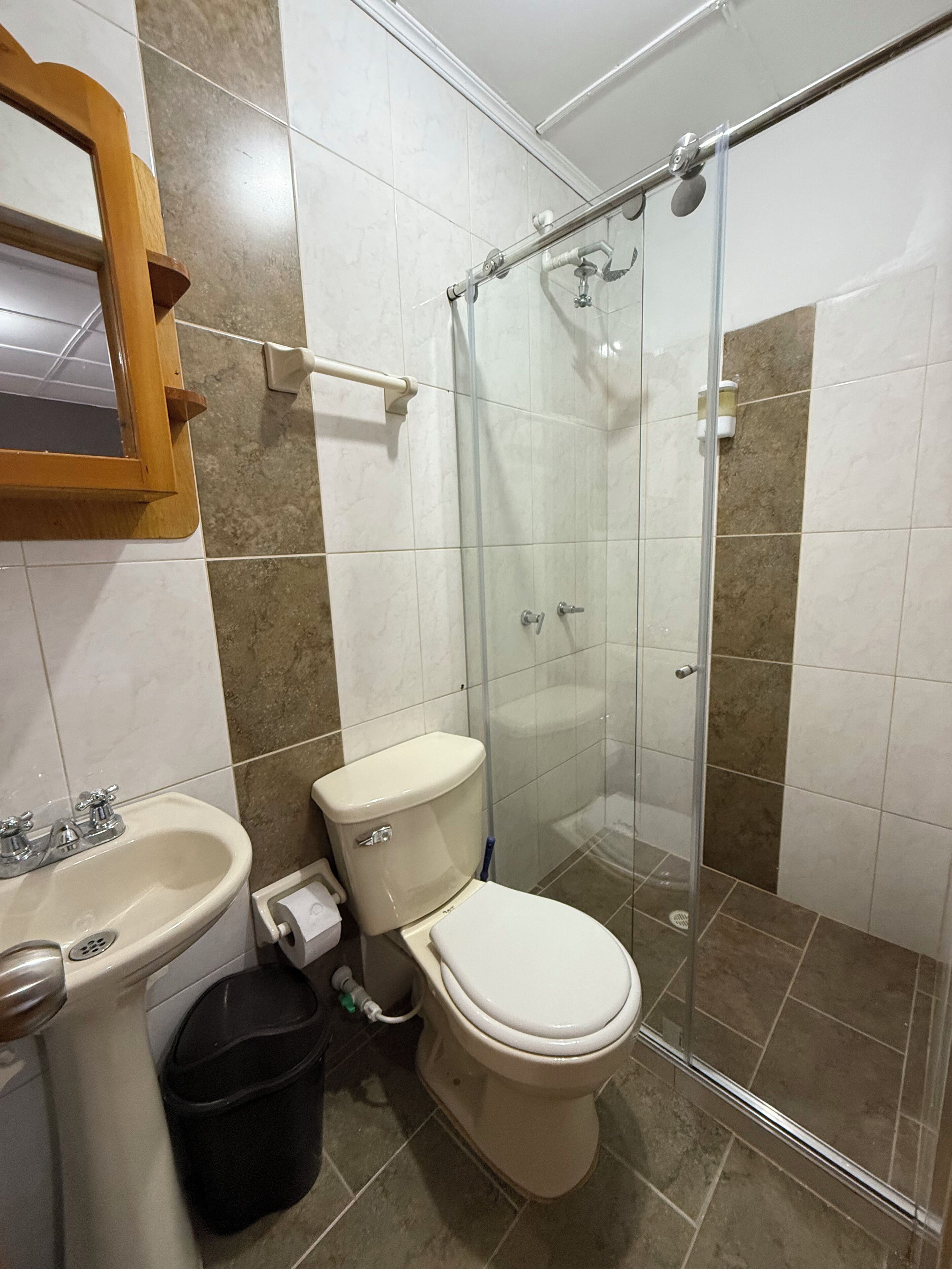 Egy fürdőszoba, amelyben WC, mosdókagyló és üvegfalas zuhanyzó található.
