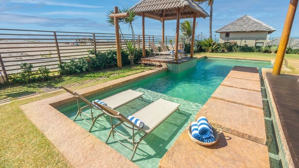 A pool area with lounge chairs, a small gazebo, and a clear view of the ocean. - Sumatera House (Trairi)